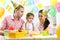 Kid with parents blow candle on birthday cake