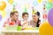 Kid with parents blow candles on birthday cake