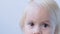Kid, part of the face, funny brown eyes close up,funny brown eyes close-up, mom is combing the girl`s blonde hair, concept of bab