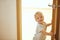 Kid peeking out looking on camera of open room door