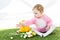 Kid in pink fluffy costume sitting near yellow ostrich egg, colorful chicken eggs and tulips isolated on white