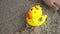 Kid play sand with hand near rubber duck