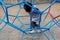 Kid playing climbing globe, metal dome climber in outdoor playground