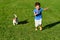 Kid playing with dog on green grass lawn dashing and racing