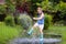 Kid playing out in the rain. Children with umbrella and rain boots play outdoors in heavy rain. Little boy jumping in muddy puddle