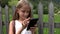 Kid playing smartphone, child browsing internet on tablet, teenager girl using technology outdoor in nature