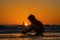 Kid playing with toy sailboat on sea beach at the summer sunset time. Sunset silhouette of child boy dreaming on cruise