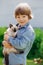 Kid plays in the summer outdoors. Ð¡hild is friends with pet in summertime. Cute toddler is playing with a kitten on grass. Boy
