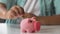 Kid putting coin in piggy bank, saving pocket money, financial literacy for kids