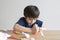 Kid putting glue stick on paper for sticking cotton wool as decorative elements for clouds on rainbow. Child Boy enjoy art