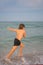 Kid running and splashing in the sea. Summer vacation. Child Running Along the beach. Active little kid running along