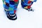 Kid`s foots in the snow with black snowy boots