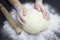 Kid`s hands, some flour, wheat dough and rolling pin on the black table. Children hands making the rye dough for backing bread.