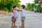 Kid in safety wearing mask in town. Twin Children wearing medical face mask outdoor. Twin Child  helps to put a mask on his face t