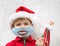 Kid in Santa hat and blue medical mask with painted funny smile . close up portrait