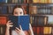 kid school girl in library hiding behind book