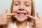 Kid showing the first milk tooth. Change teeth concept. Cute little girl with blonde hair on gray background