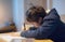 Kid siting on table doing homework,Child boy holding black pen writing on white paper,Young boy practicing English words at home.