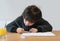 Kid siting on table doing homework,Child boy holding pencil writing on white paper,Young boy practicing  English words at home.