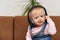 Kid sits in the headphones and smiles. Baby listens to music