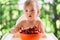 Kid sits at a table on the balcony in front of cherries on a plate