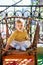 Kid sits on a wicker chair standing on a colored rug on the balcony