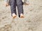 Kid sitting with feet against a sand in summer playground