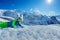 Kid skier having fun laying in snow over mountains