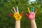 Kid with smiling face drawn on palms in park, closeup. School holidays