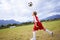 Kid, soccer ball and playing on green grass for sports, training or practice with clouds and blue sky. Young football