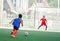 Kid soccer player run to shoot ball to goal with blurry goalkeeper background on green artificial turf, Football or soccer academy