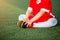 Kid soccer players is sitting with warming on green artificial turf for stretch muscles