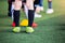 Kid soccer players standing with blurry cone marker on green artificial turf