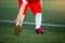 Kid soccer players is standing and warming on green artificial turf for stretch muscles before