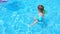 Kid splashing on summer pool. Excited toddler boy splashing water.