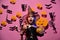 Kid in spooky witches costume holds carved pumpkin and chandelier