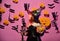 Kid in spooky witches costume holds carved pumpkin and chandelier