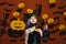 Kid in spooky witches costume holds old gas lamp.Haloween party and decorations concept. Little witch wearing black hat