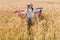 Kid in straw hat holding american flag in golden field