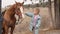 kid stroking a beautiful brown harnessed horse with a white spot