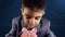 Kid in a suit looking down at the piggy bank. Stock market chart in the background. Financial education, savings for