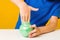 Kid takes green slime from bottle. Child plays with slime toy on white table, cropped image. Popular toys