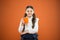 Kid tested breakfast. Little child having tea or milk for breakfast on orange background. Happy cute pupil holding book