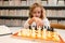 Kid thinking of chess. Little child chessman play chess game, checkmate.