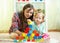 Kid toddler and mother build tower playing wooden toys at home or nursery