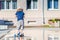 Kid toddler riding his scooter in a city. Summertime fun activity. Caucasian white boy is wearing a hat.