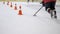 Kid training hockey and handling puck with obstacles between road cones on the ice inside rink