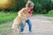 Kid training, playing with dog outdoors. Little girl takes the spitz in her arms. child hugging a pet. Happy baby is walking with