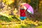 Kid with umbrella playing in autumn rain