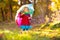 Kid with umbrella playing in autumn rain